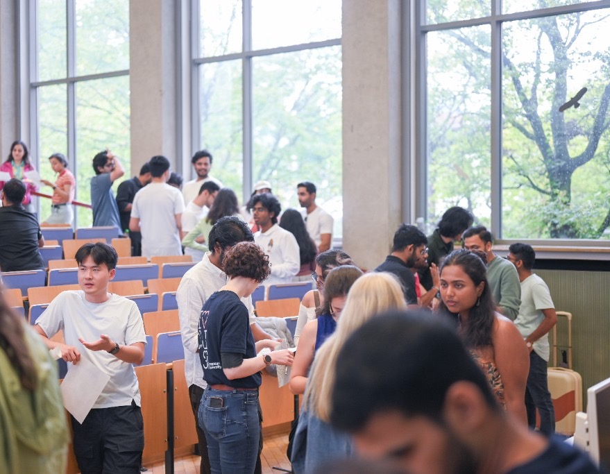 Young adults talking in small groups during a collaborative workshop in a lecture hall