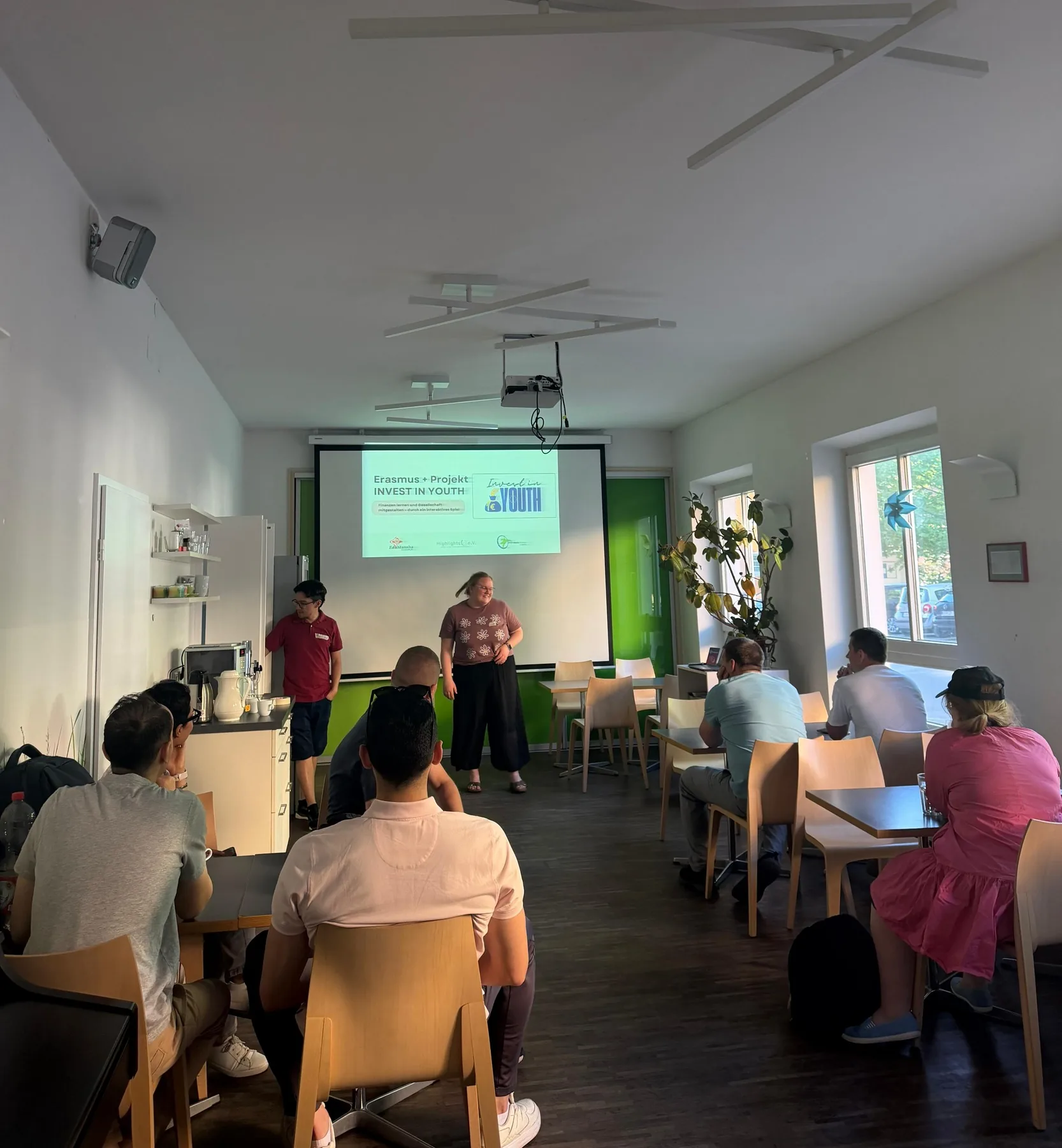 Workshop room in Nürnberg with participants seated at tables while facilitators present the Erasmus+ Invest in Youth project.